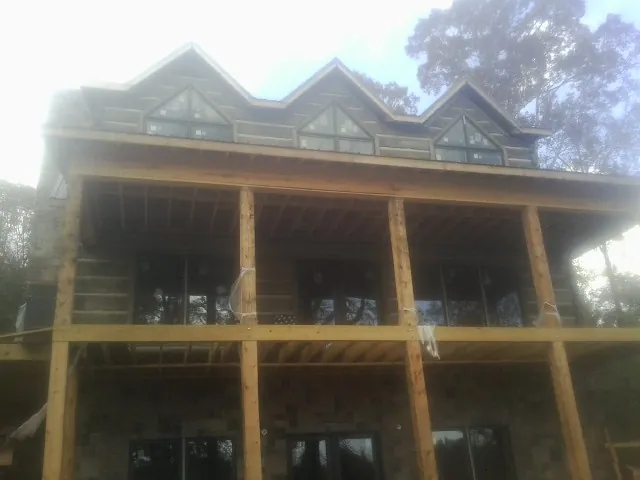 Dormers and porch framing on a large log home under construction — Roof Coating work by our crew in Corning