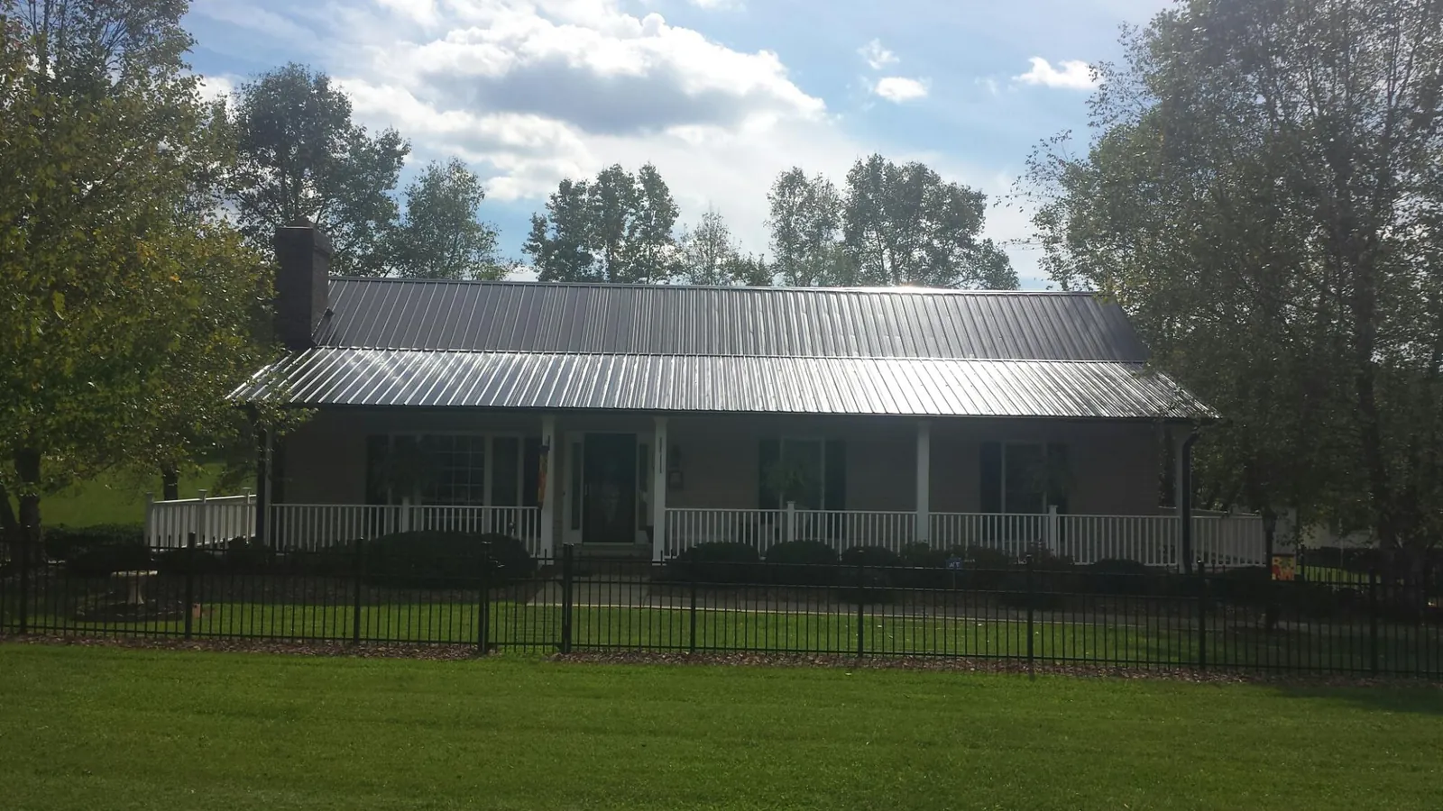 Gray metal roof on a brick ranch with a full width front porch — Gutter Guard Installation work by our crew in Corning